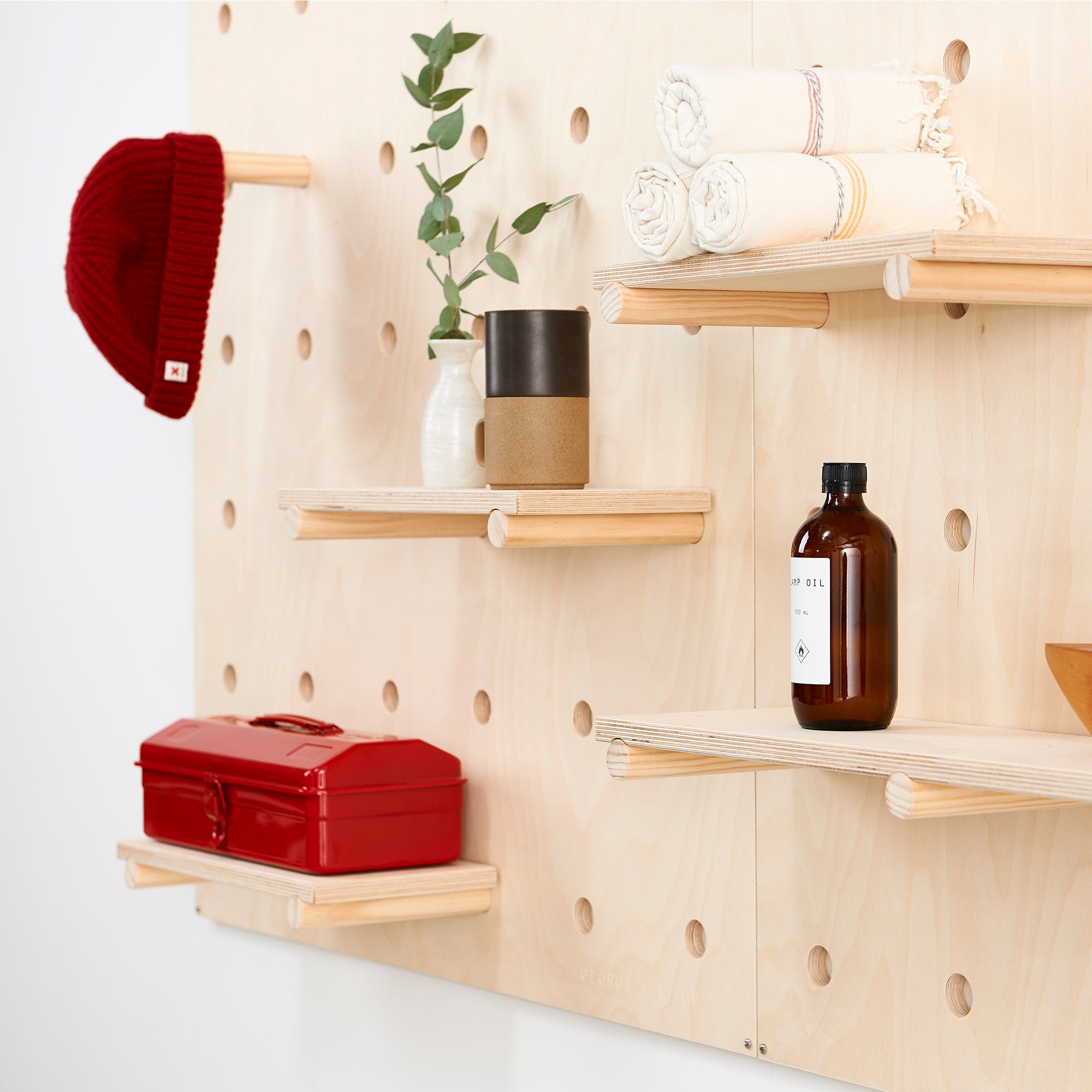 A wooden pegboard with dowel pegs and shelves designed for storing belongings or displaying products in a store